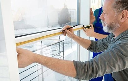 Monteur beim Aufmaß eines Fensters mit dem Maßband