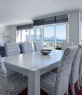 Essbereich mit raumhoher Fensterfront und Panoramablick über die Bucht